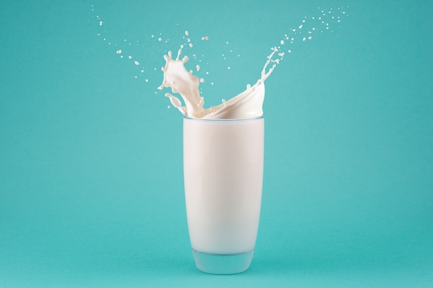 Splashes of milk in a glass isolated on blue background