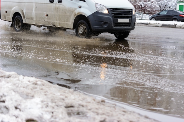 The splashes water from under the wheels of a vehicle moving through spring dirty puddles from melted snow. Flood waters in the aftermath of a blizzard.