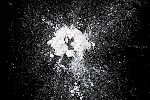 Photo splashing of natural white flour powder on black board top view as texture or background