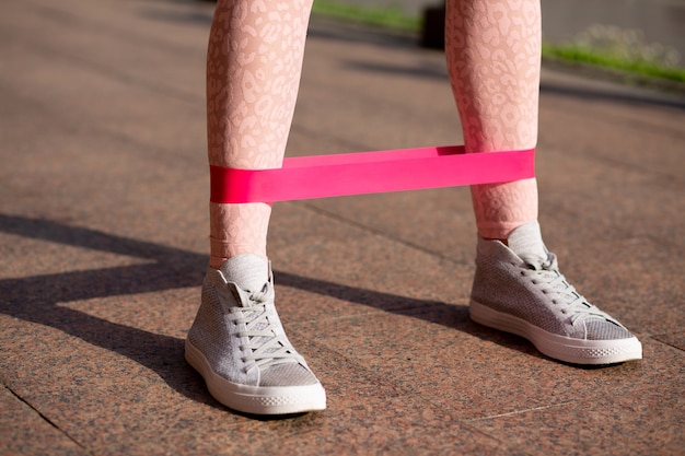 Splendid fit woman doing legs workout with rubber resistance band at the park