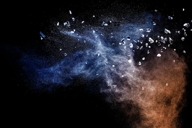 Split debris of stone exploding with blue powder against black background