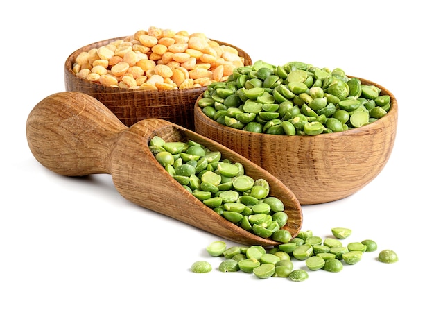 Split dried green and yellow peas in a wooden bowl and scoop close-up isolated on white background