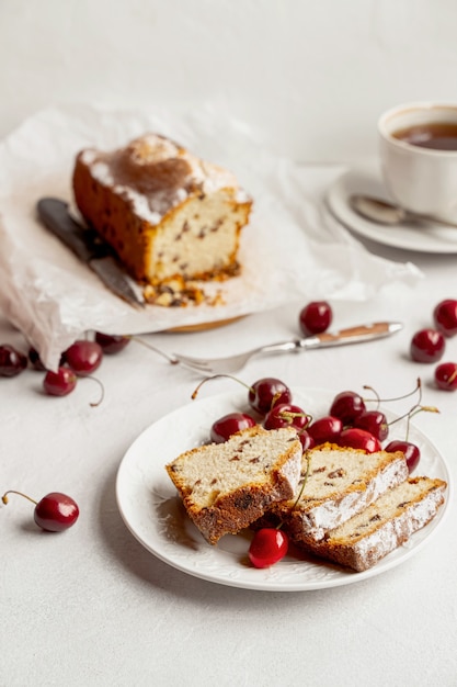 Sponge cake and sweet cherries on a table set for tea.