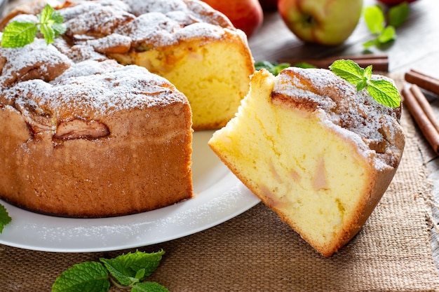 Sponge cake with apples on a wooden board on the table.