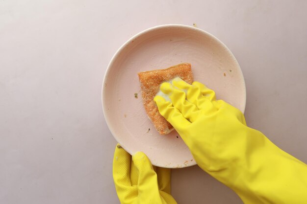 Sponge rubber gloves and colorful plate on blue