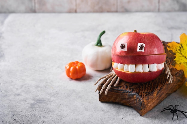 Spooky green kiwi monsters for Halloween Healthy Fruit Halloween Treats Halloween party kiwi strawberry apple and marshmallow monster on grey stone or concrete table background Selective focus