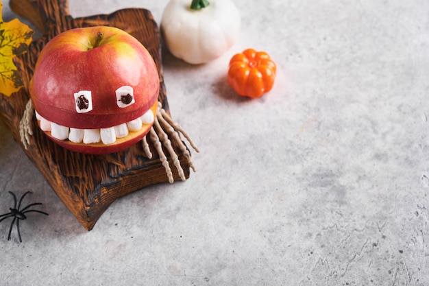 Spooky green kiwi monsters for Halloween Healthy Fruit Halloween Treats Halloween party kiwi strawberry apple and marshmallow monster on grey stone or concrete table background Selective focus