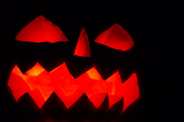 Spooky Halloween pumpkin jackolantern with burning candles on dark background