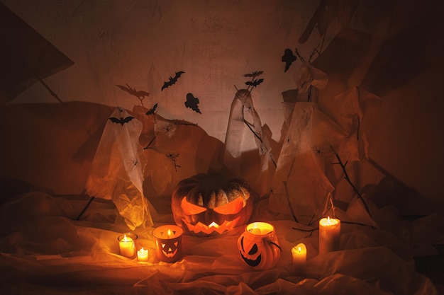 Spooky Jack o lantern carved pumpkin spider web ghost bats and glowing light in dark Happy Halloween Scary atmospheric halloween party decorations space for text Trick or treat