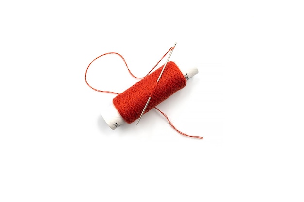 Spool of red thread with a needle isolated on white background Red thread and needle isolated on white background