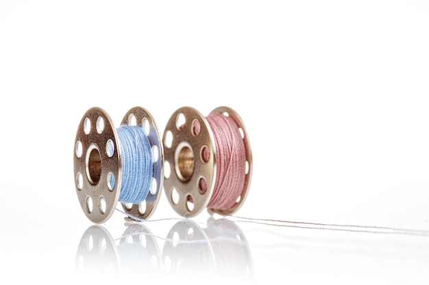 Spools of blue and pink thread on a white background