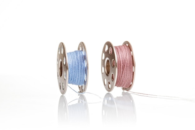 Spools of blue and pink thread on a white background