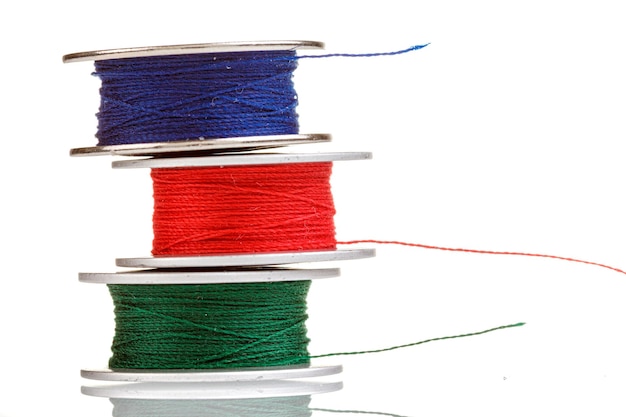 Spools of thread in blue red green colors on a white background