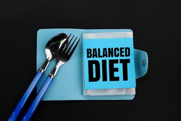 spoon fork and book with the word balanced diet the concept of nutritional balance or taking care