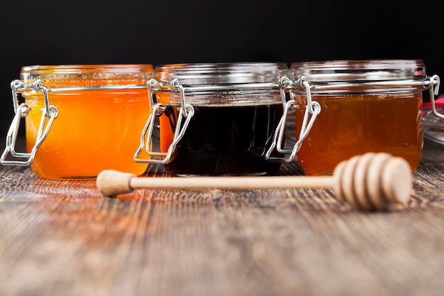 A spoon for honey together with high-quality bee honey, an old table on which there is a healthy and sweet bee honey and a wooden special spoon