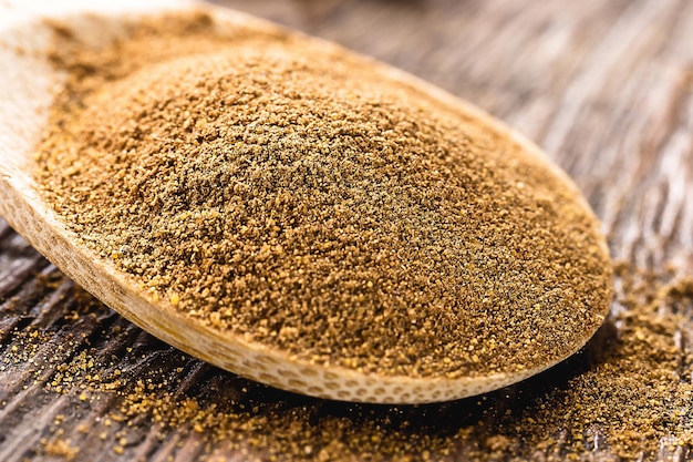 spoon of powdered cinnamon spice obtained from the inner bark of several species of trees of the genus Cinnamomum used in both sweet and savory foods