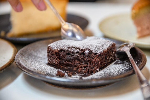 Spoon scooping chocolate brownie with icing powder