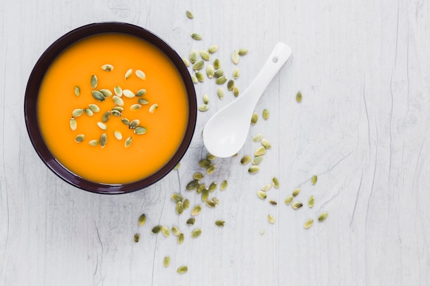 Spoon and seeds near pumpkin soup