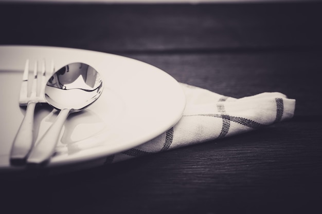 spoon in white dinner plate on wooden table close up