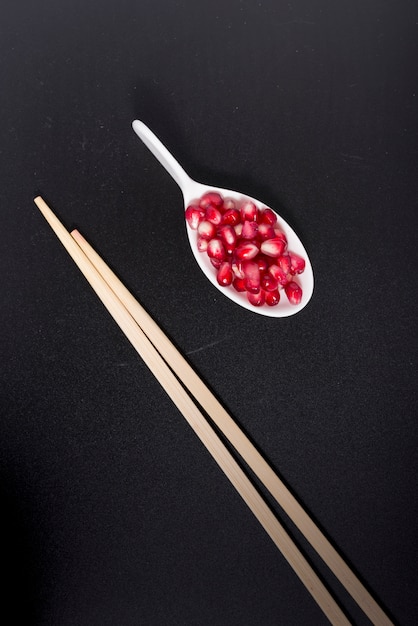 Photo spoon with pomegranate seeds and chopsticks