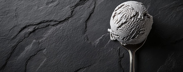 Photo spoon with scoop of vanilla ice cream on dark stone background