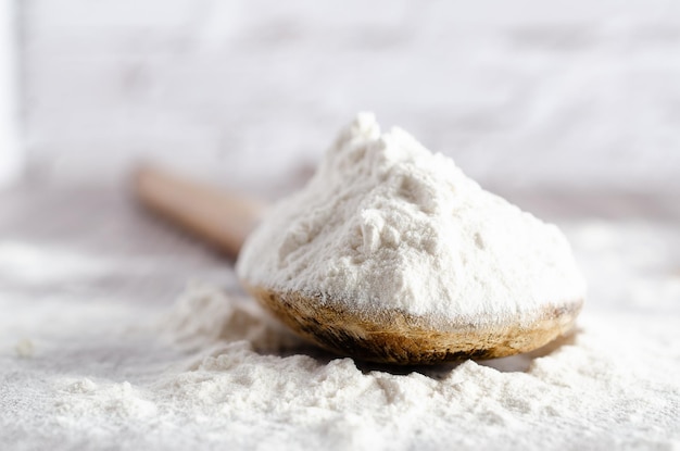 A spoonful of white flour on wooden backdrop with copy space.