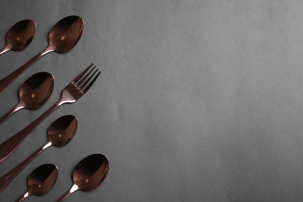 Spoons and fork on grey background flat lay Space for text