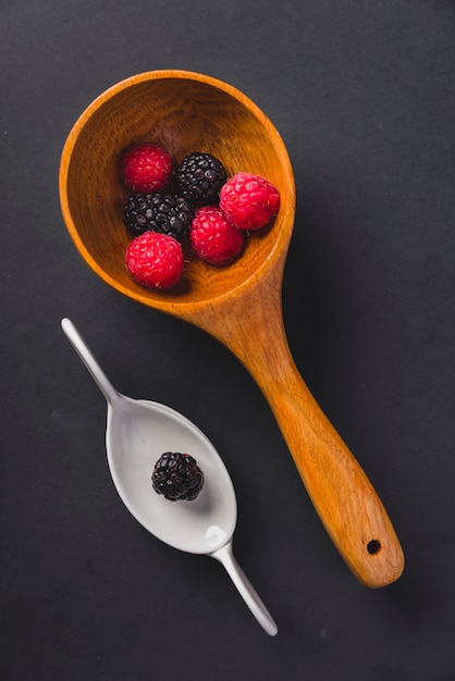 Spoons with raspberry and blackberries background black