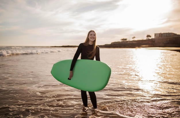 Sport activities portrait of cheerful young surfer woman posing with surfboard