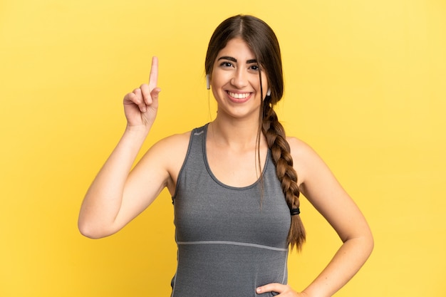 Sport caucasian woman isolated on yellow background pointing up a great idea