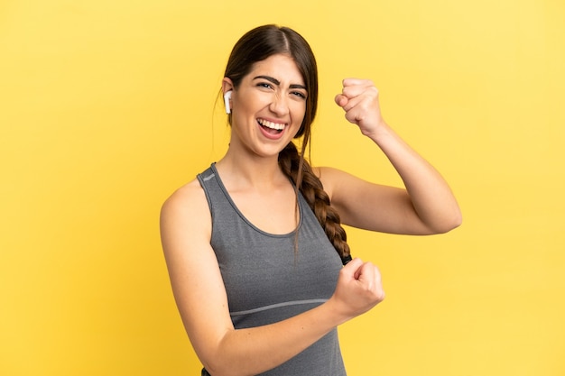 Sport caucasian woman isolated on yellow surface celebrating a victory