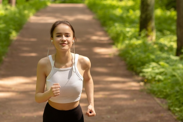 Sport diet healthy lifestyle Girl in headphones runs in the park smiling