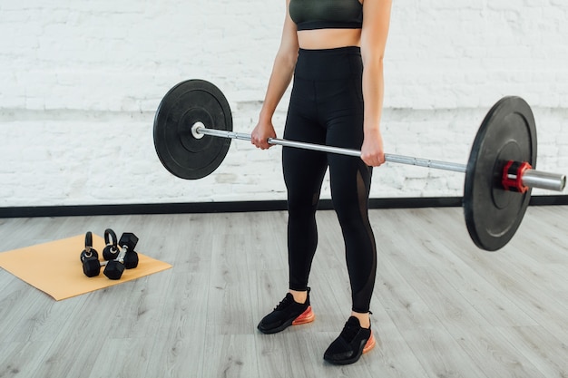 Sport equipment. Brunette woman holding barbell!