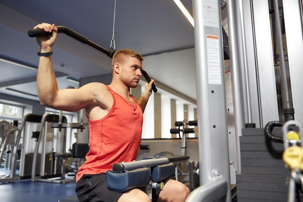 sport, fitness, bodybuilding, lifestyle and people concept - man exercising and flexing muscles on cable machine in gym