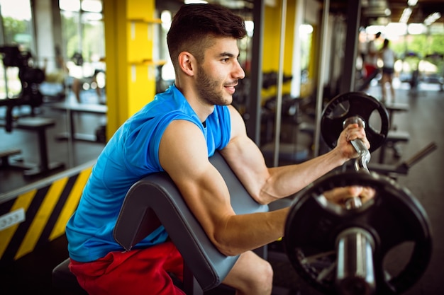 Sport, fitness, lifestyle and people concept. Happy young fit man exercising with dumbbells in gym