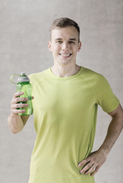 sport, fitness, lifestyle and people concept - smiling man with bottle of water in gym