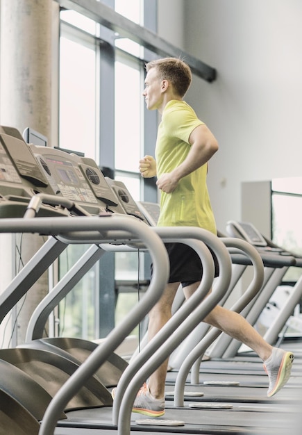 sport, fitness, lifestyle, technology and people concept - smiling man exercising on treadmill in gym