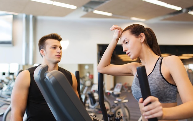 sport, fitness, lifestyle, technology and people concept - tired woman with trainer exercising on stepper in gym