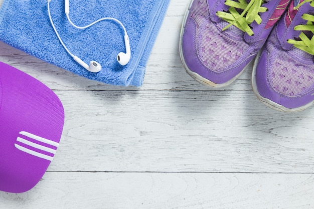 Sport flat lay purple shoes and cap on white wooden background