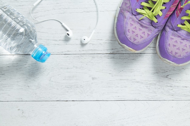 Sport flat lay purple shoes and workout equipments on white wooden background. 