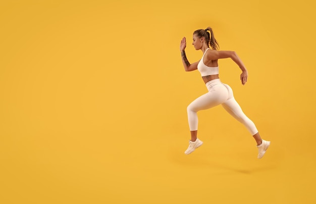 Sport girl runner running with copy space on yellow background