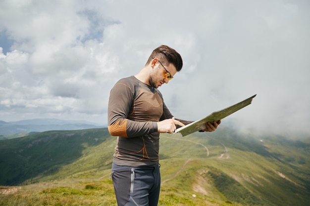 Sport hiker standing with map on the mountain trail