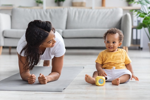 Sport At Home Young Black Mom Making Plank Exercise With Little Baby