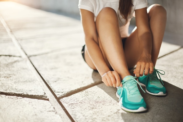 Sport is the way of life. Close-up of runner sneakers tying laces getting ready to run. Urban sport concept.