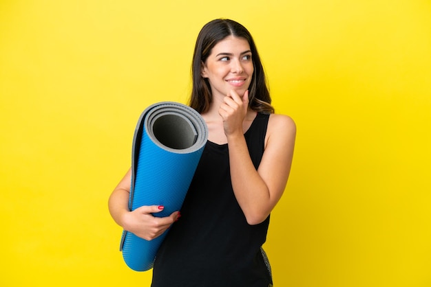 Sport Italian woman going to yoga classes isolated on yellow background looking to the side and smiling