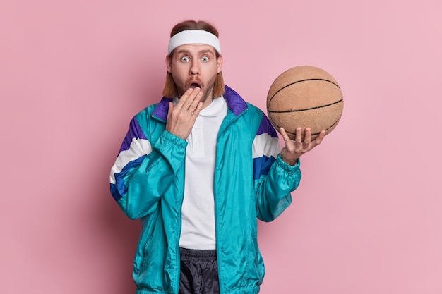 Sport leisure lifestyle concept. Stupefied unshaven sportsman basketball player holds ball dressed in sports clothes going to play game with friends being active 