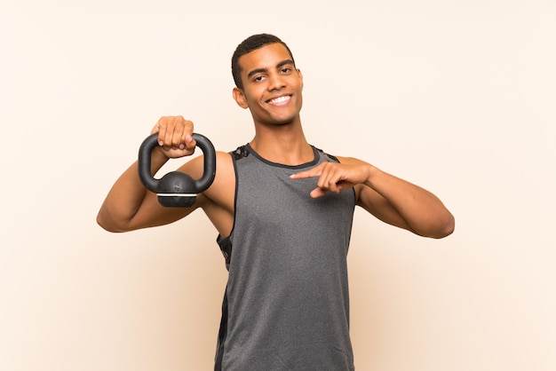 Sport man over isolated wall with kettlebell