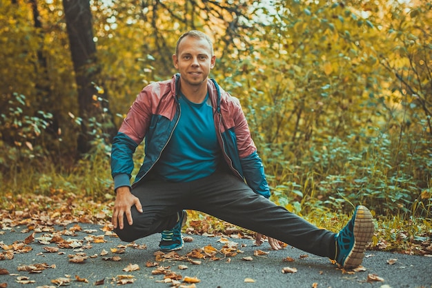 Sport man stretching at the park autumn doing exercises Fitness concepts