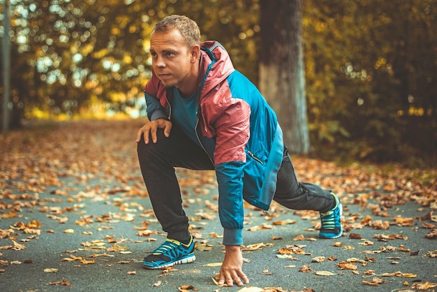 Sport man stretching at the park autumn doing exercises Fitness concepts