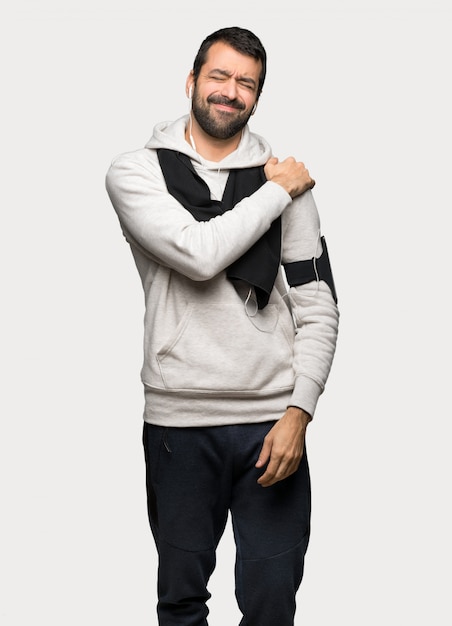 Sport man suffering from pain in shoulder for having made an effort over isolated grey background